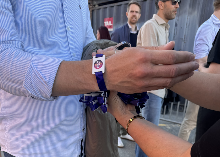 Påsætning af vævet lilla armbånd med RFiD-chip for adgangskontrol til event.